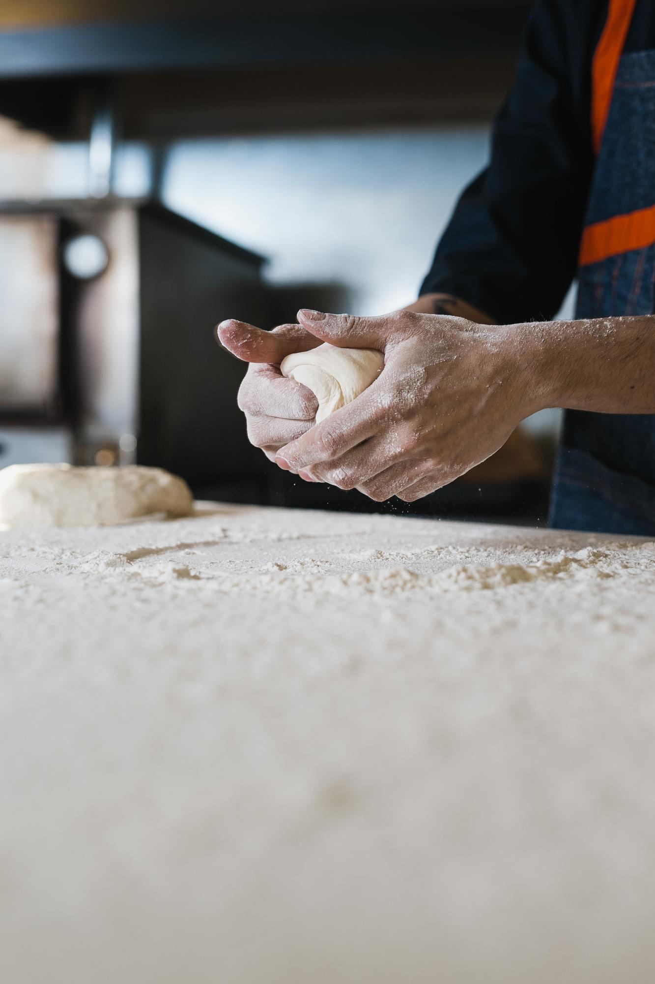 Close up of hands shaping dough on marble